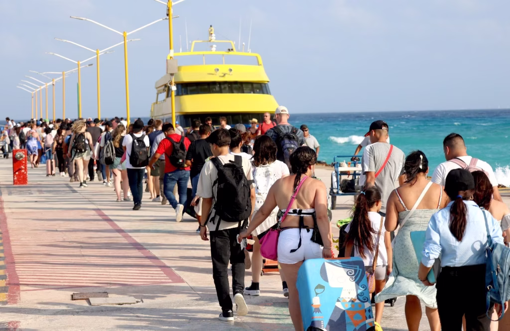 Visitantes nacionales y extranjeros caminan por un muelle turístico en Playa del Carmen, uno de los destinos con mayor crecimiento turístico y presión urbana en Quintana Roo.
