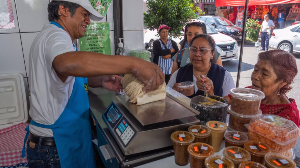 Personas compran alimentos básicos en mercado popular de México