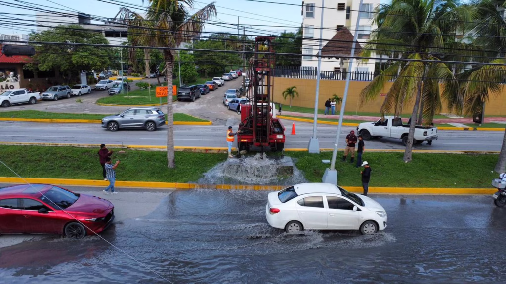 Vehículos circulan entre encharcamientos provocados por lluvias intensas en Cancún.
