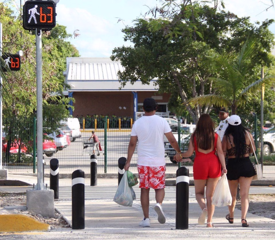Personas cruzan una vialidad urbana utilizando infraestructura peatonal en Quintana Roo