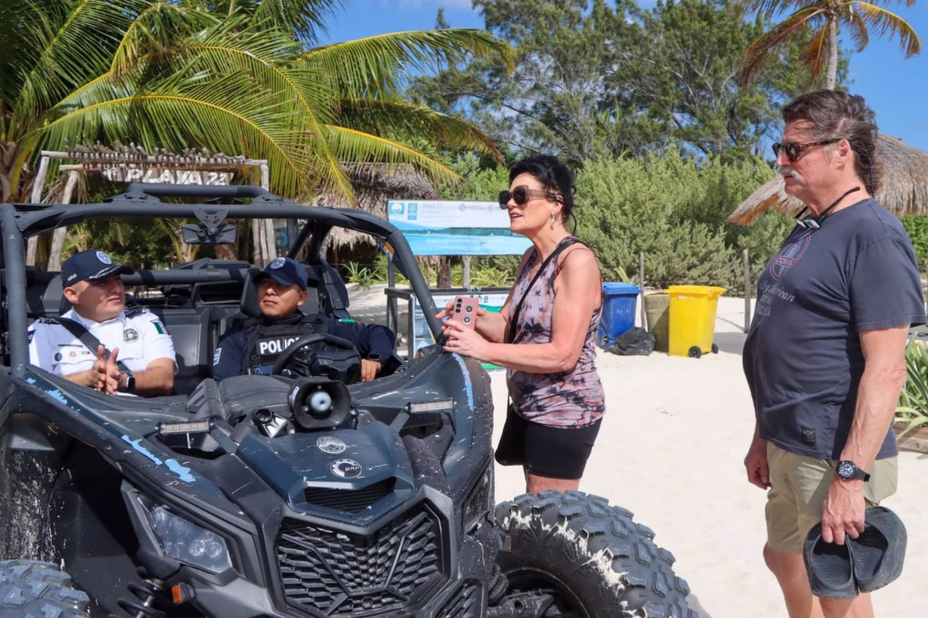 Elementos de la Policía Turística de Playa del Carmen atienden a visitantes desde una patrulla durante labores de vigilancia y proximidad.