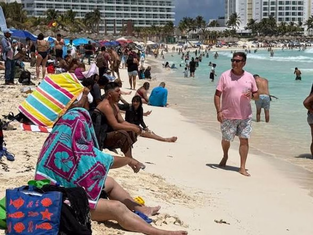 Turistas disfrutan una playa de Cancún durante la temporada de verano, una imagen que representa la actividad del turismo en Quintana Roo y la afluencia de visitantes al Caribe Mexicano.