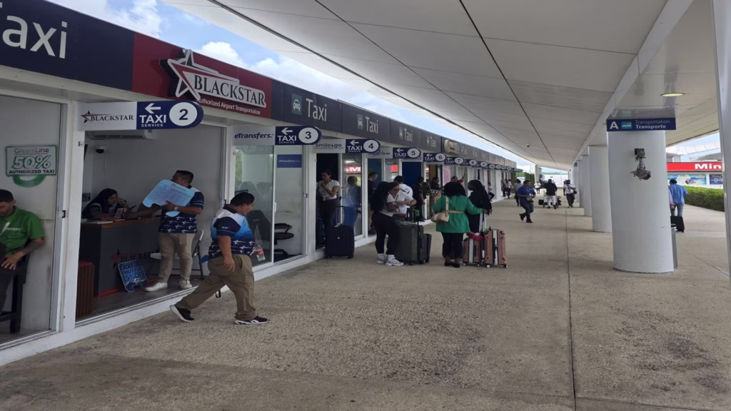 Taxis y pasajeros en el área de transporte terrestre del aeropuerto de Cancún.