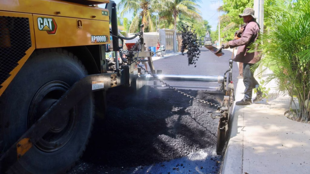 Trabajadores colocan carpeta asfáltica durante una obra pública en Puerto Morelos.