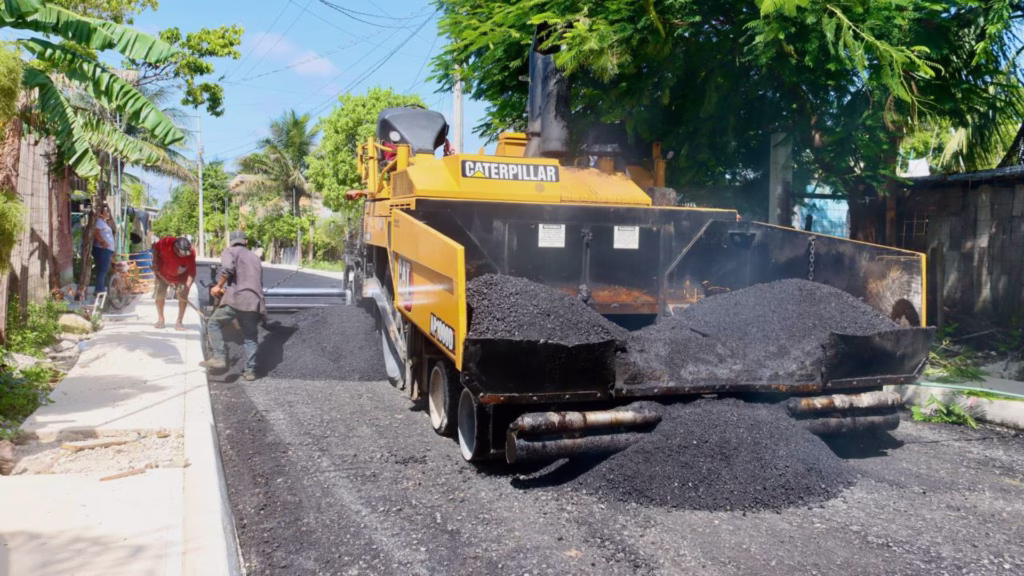 Trabajadores colocan carpeta asfáltica durante una obra pública en Puerto Morelos.