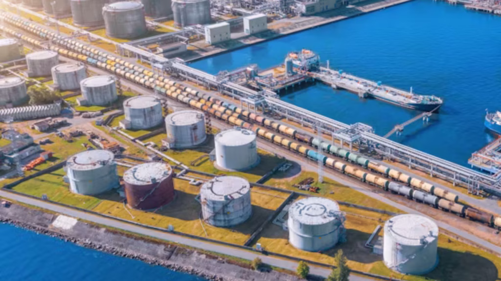 Terminal de combustibles con tanques de almacenamiento, carros ferroviarios y un buque atracado.