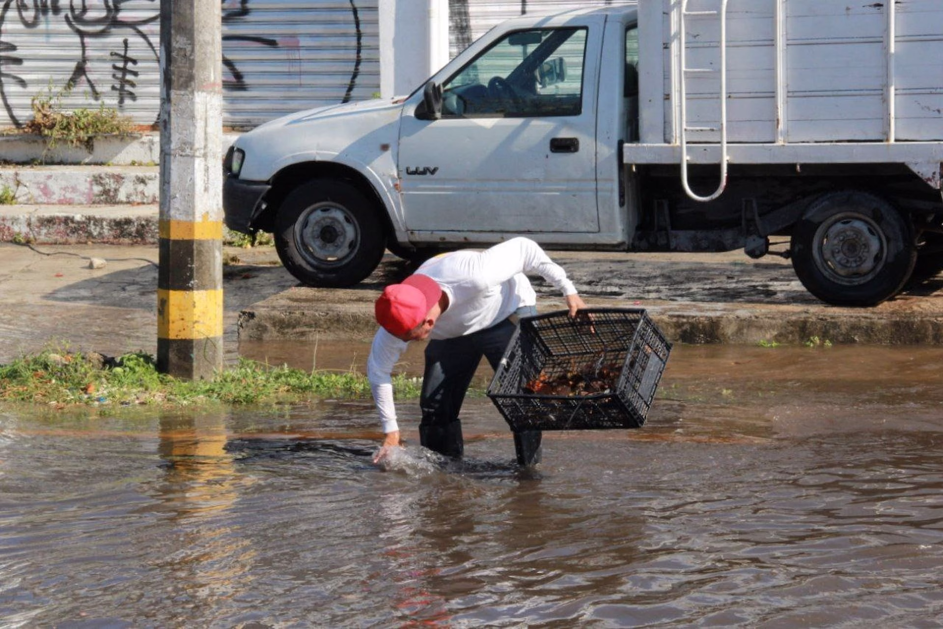 Trabajador realiza labores de desazolve en una calle afectada por las lluvias en Quintana Roo.