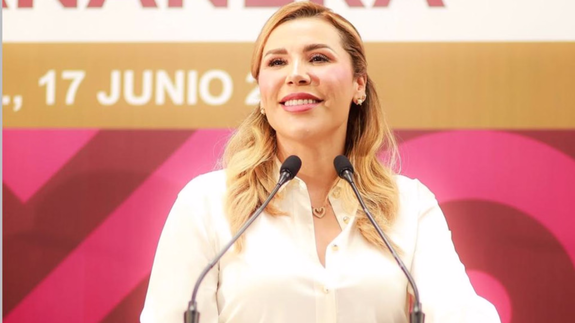 Marina del Pilar habla frente a dos micrófonos durante un acto público en Baja California.