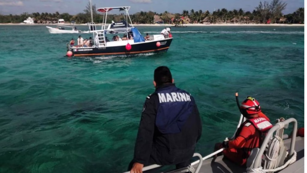 Elementos de la Secretaría de Marina observan una embarcación turística durante un operativo de seguridad y auxilio marítimo.