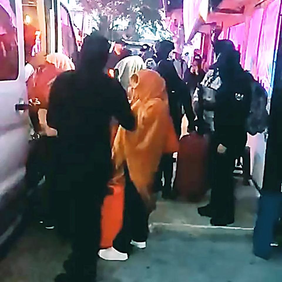 Personal de seguridad acompaña a mujeres con equipaje durante un operativo de la FGE de Quintana Roo en 2025.