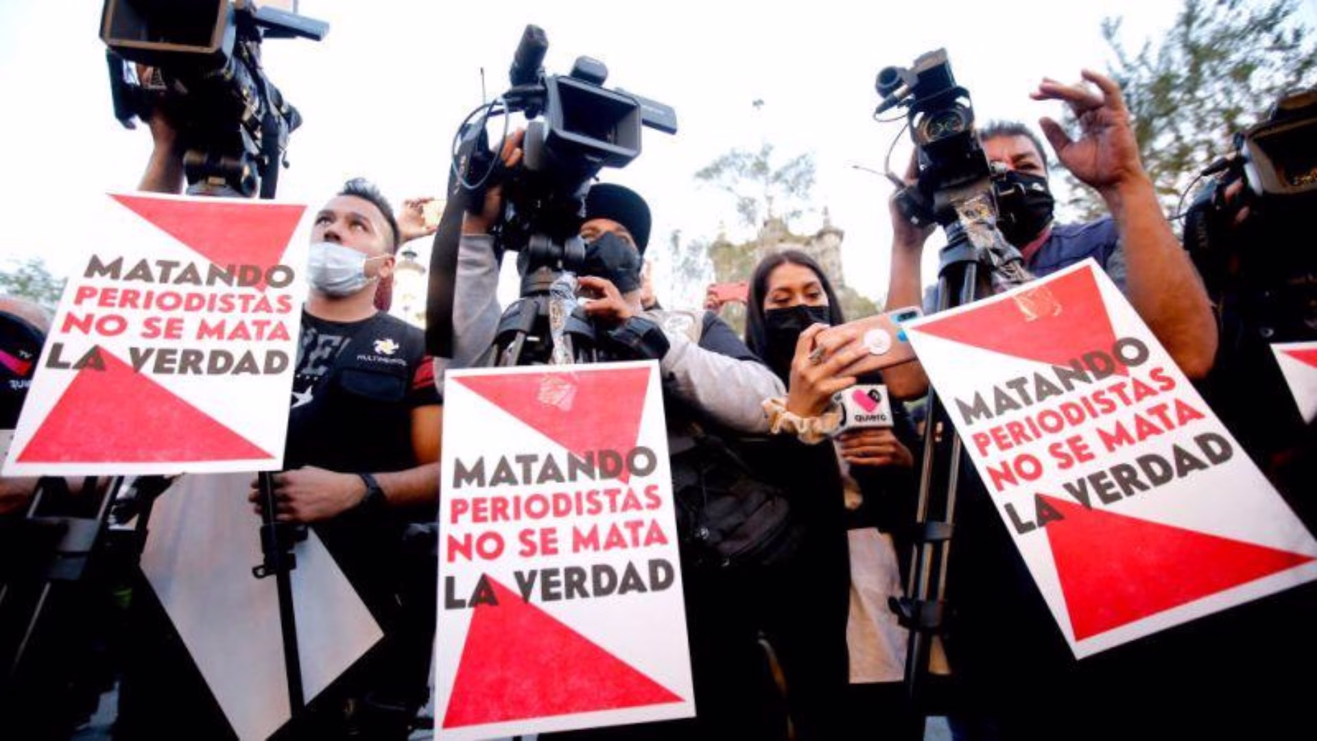 Periodistas con cámaras sostienen carteles contra los asesinatos de comunicadores en México