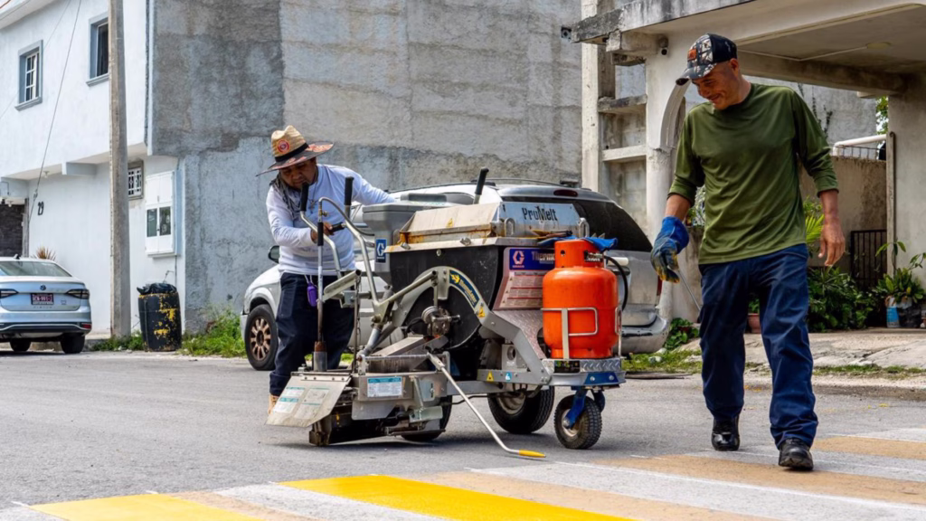 Personal municipal utiliza pintura termoplástica para marcar un cruce escolar como parte del programa vial de Cozumel.