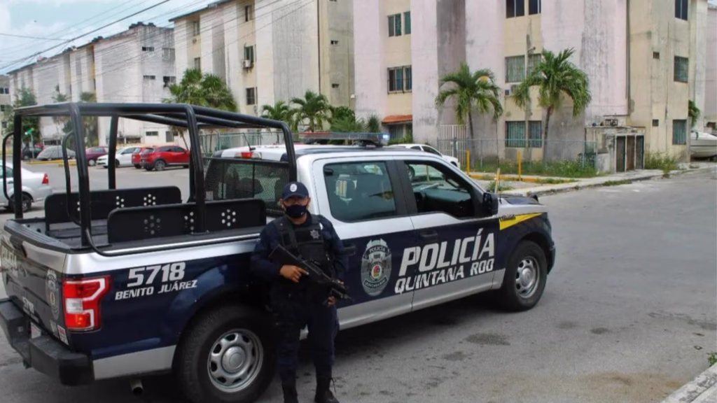 Policía de Quintana Roo permanece junto a una patrulla identificada con el municipio de Benito Juárez.