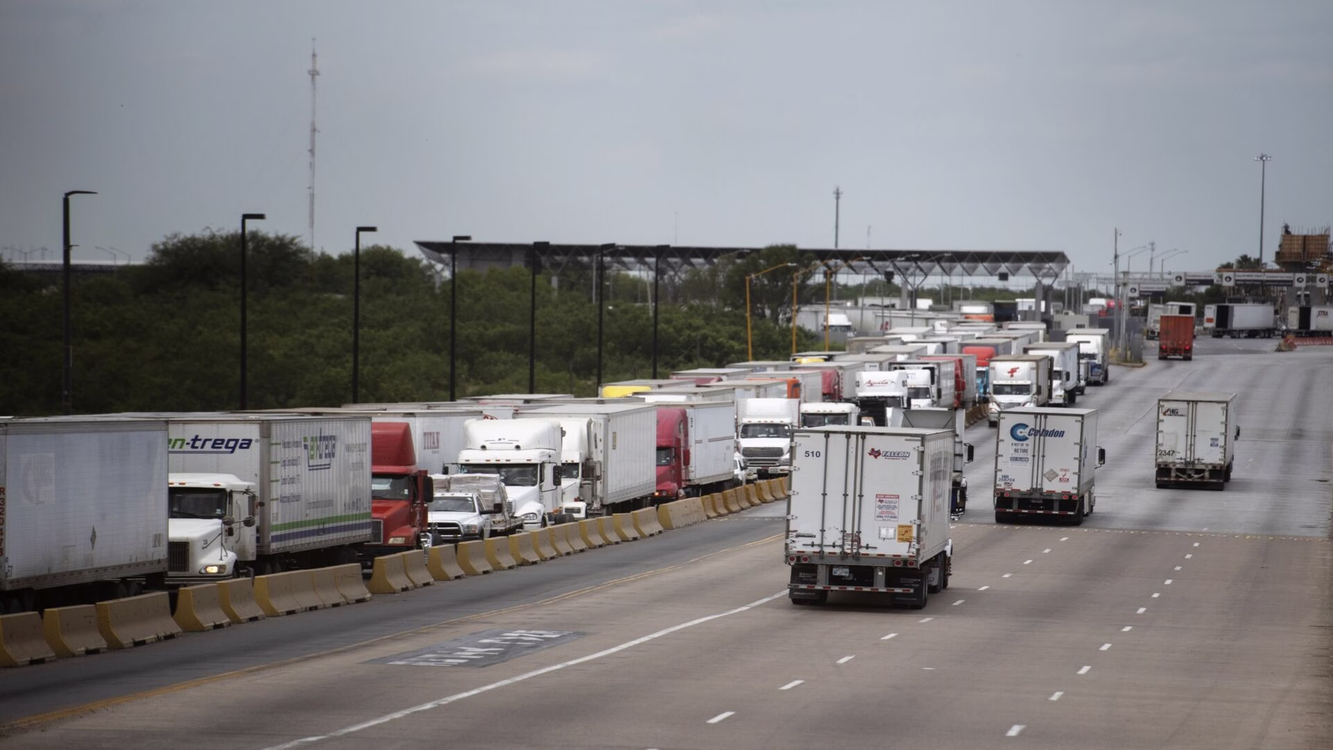 Camiones de carga circulan por un cruce fronterizo, donde el comercio entre México y Estados Unidos enfrenta nuevas exigencias del T-MEC.