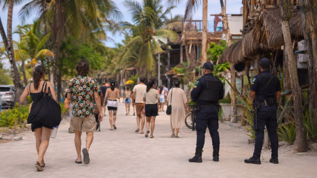 Turistas recorren una zona peatonal de Quintana Roo con presencia de elementos policiales, como muestra de la relación entre seguridad y turismo.