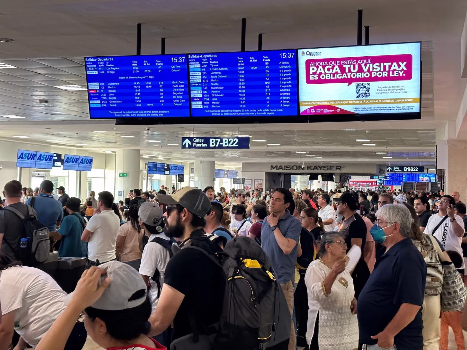 Pasajeros esperan frente a las pantallas de vuelos en una terminal del Aeropuerto Internacional de Cancún.