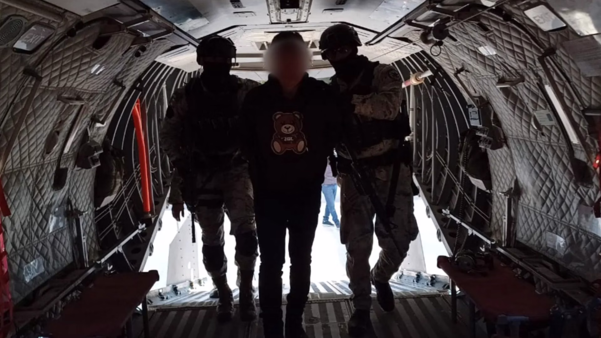 Persona detenida es trasladada dentro de una aeronave bajo custodia de elementos federales.