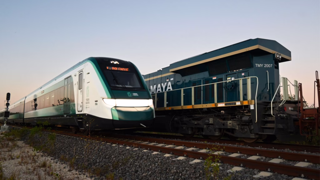 Convoy de pasajeros del Tren Maya junto a una locomotora del servicio ferroviario de carga.