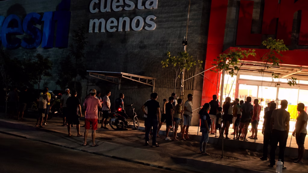 Grupo de personas reunidas durante la noche frente a un establecimiento, en medio de una movilización registrada en la zona.
