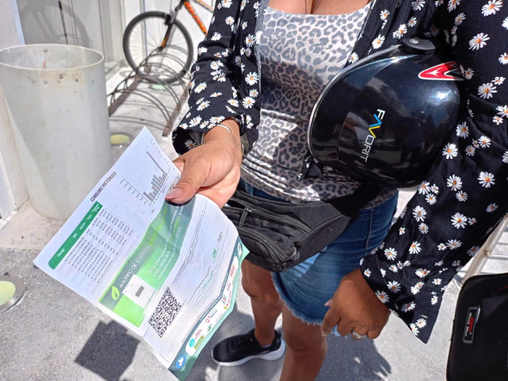 Una habitante muestra su recibo de la Comisión Federal de Electricidad mientras reclama por los constantes apagones en Playa del Carmen.