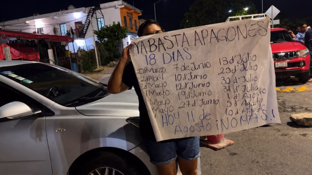 Vecina muestra un cartel con fechas de apagones durante una protesta en Playa del Carmen.
