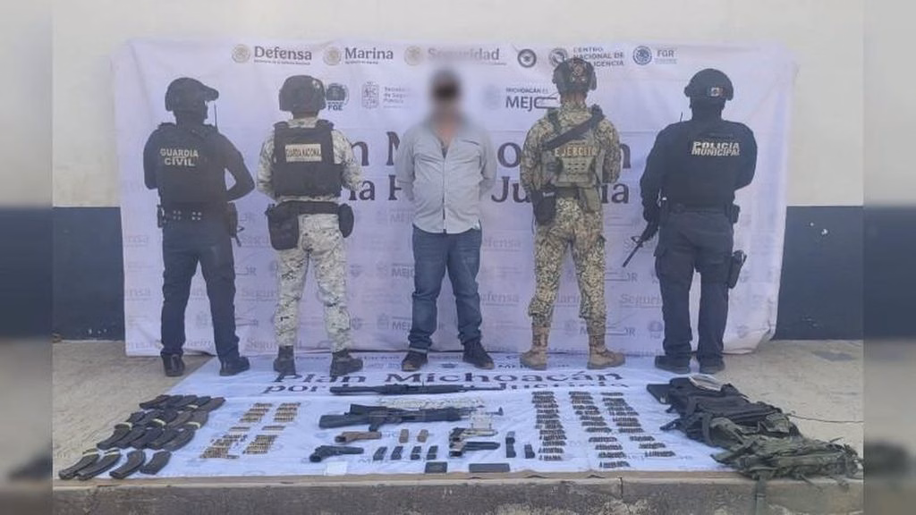 Fuerzas de seguridad presentan a una persona detenida junto con armamento y otros objetos asegurados.