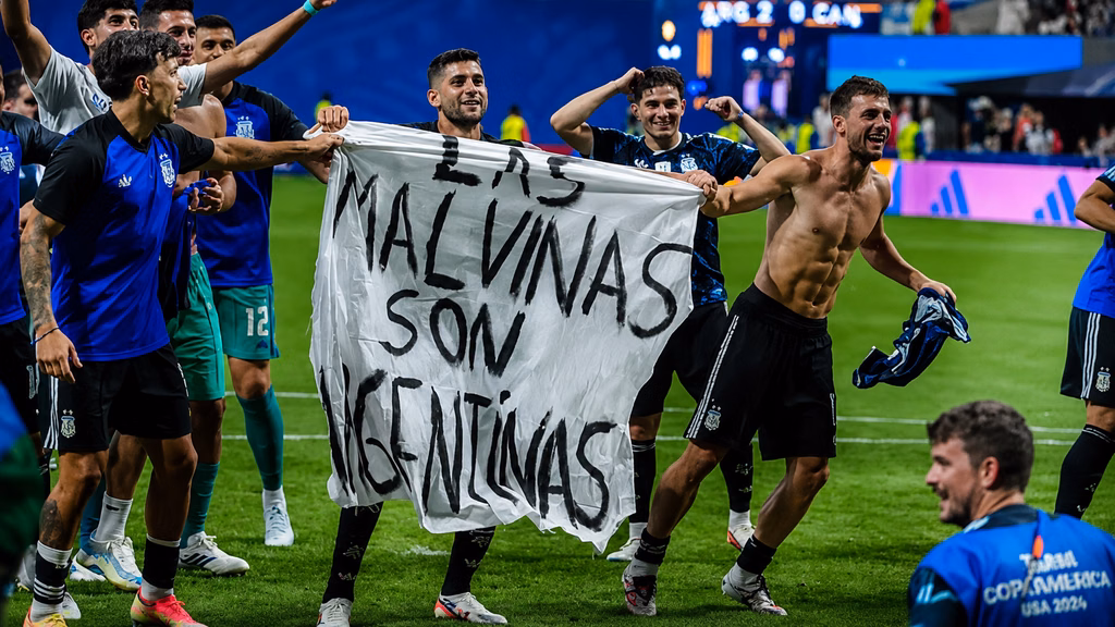 Futbolistas argentinos exhiben una manta con la frase “Las Malvinas son argentinas” durante una celebración.