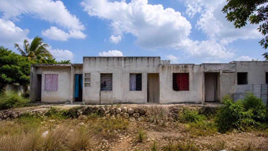 Fachada de viviendas ubicadas en una zona sin urbanización completa, como parte del contexto de la regularización de predios de In House en Playa del Carmen.