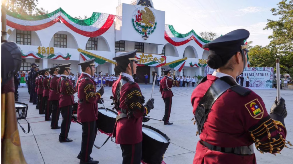 Integrantes de una banda de guerra participan en una ceremonia cívica frente al Palacio Municipal de Cancún decorado por Fiestas Patrias.