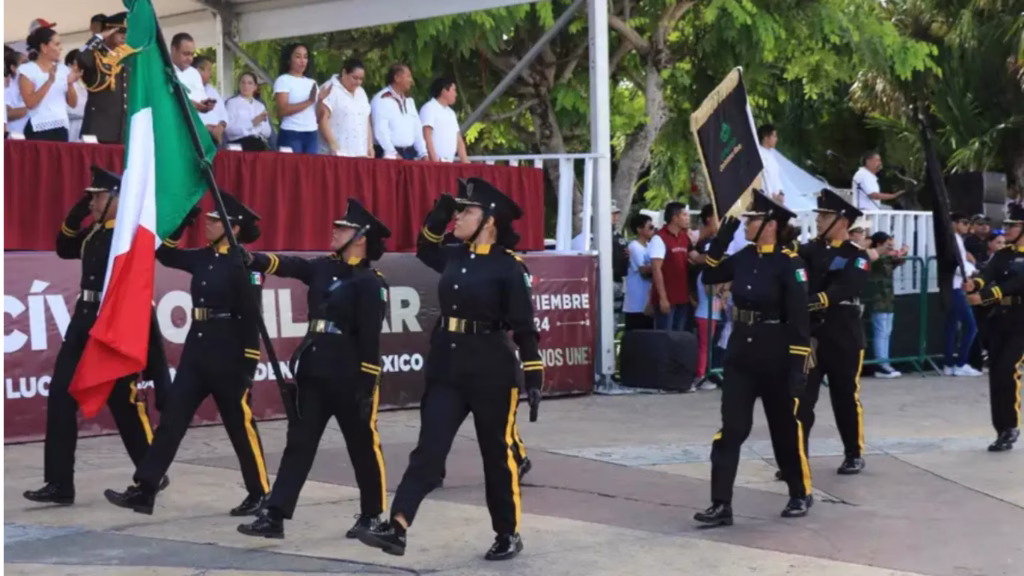 Escolta cívica porta la Bandera Nacional durante una ceremonia de Fiestas Patrias en Cancún.