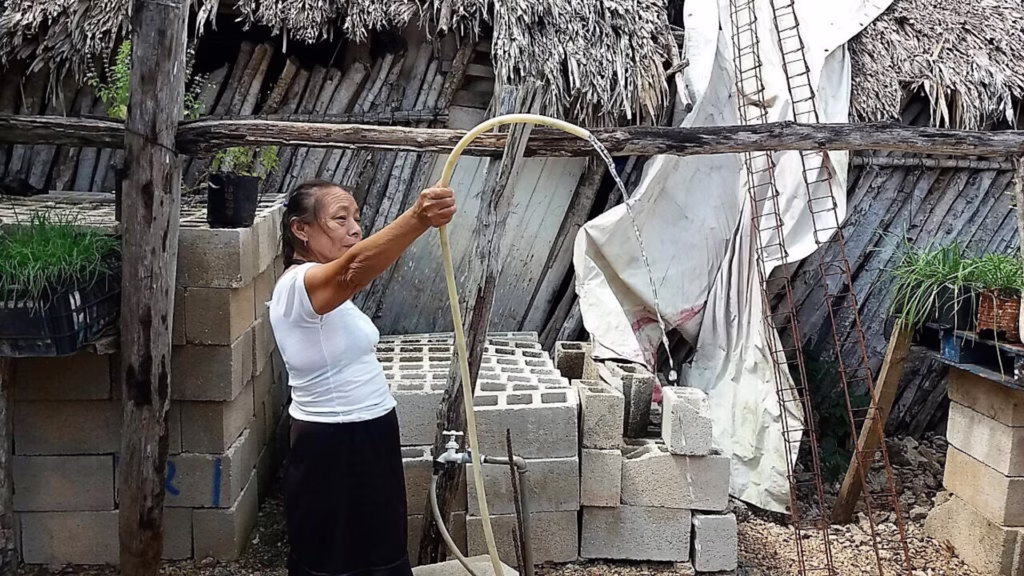 Mujer utiliza una manguera para abastecerse de agua en una comunidad de Lázaro Cárdenas, Quintana Roo.