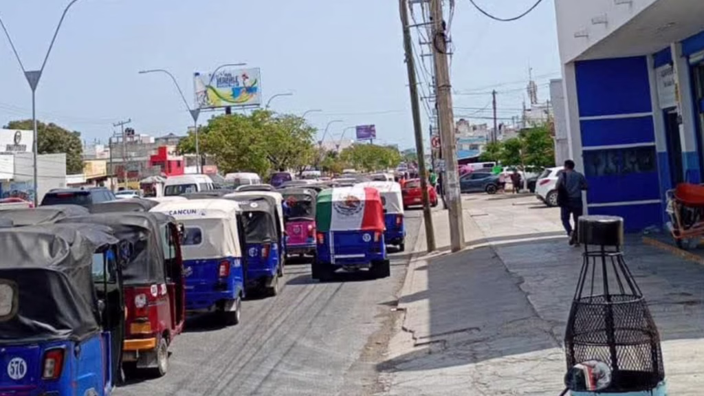 Caravana de mototaxis circula por una avenida de Cancún durante una protesta del sector.