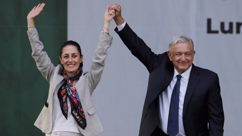 Claudia Sheinbaum y Andrés Manuel López Obrador levantan las manos durante un acto público